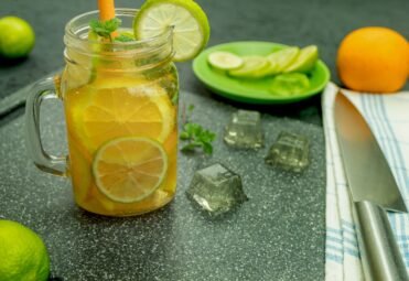 Cool lemonade made from orange and ice cubes. Water drops. Refreshing fruit drink on a rustic wooden background. Background with space for text